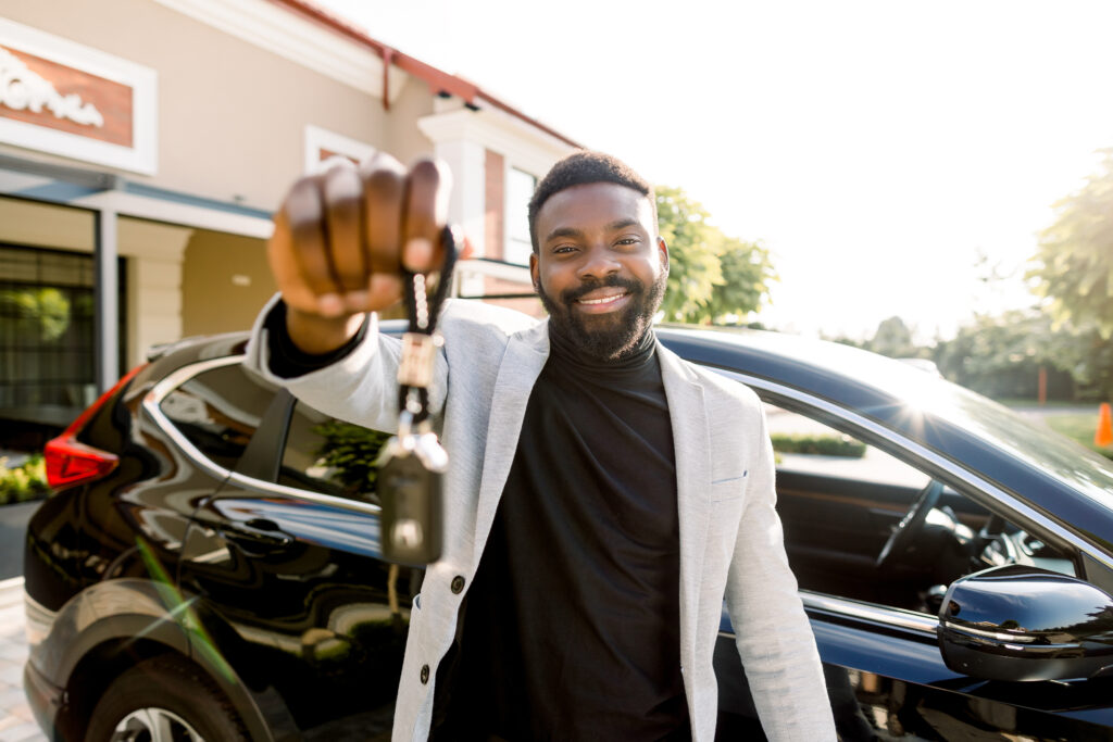 Porträt eines afroamerikanischen Mannes, der die Schlüssel zu seinem neuen Auto hält.