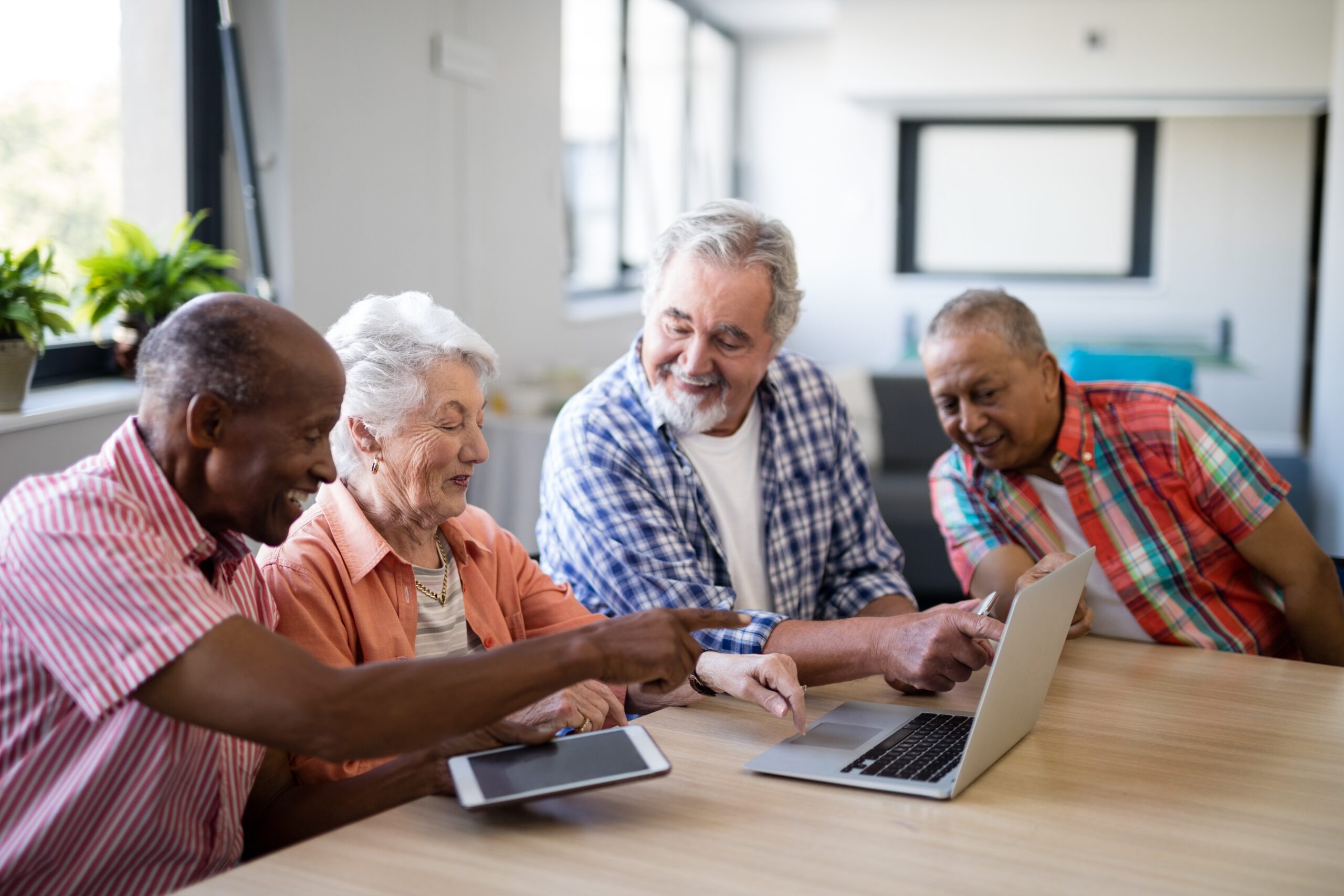 A group of smiling older adults using a laptop