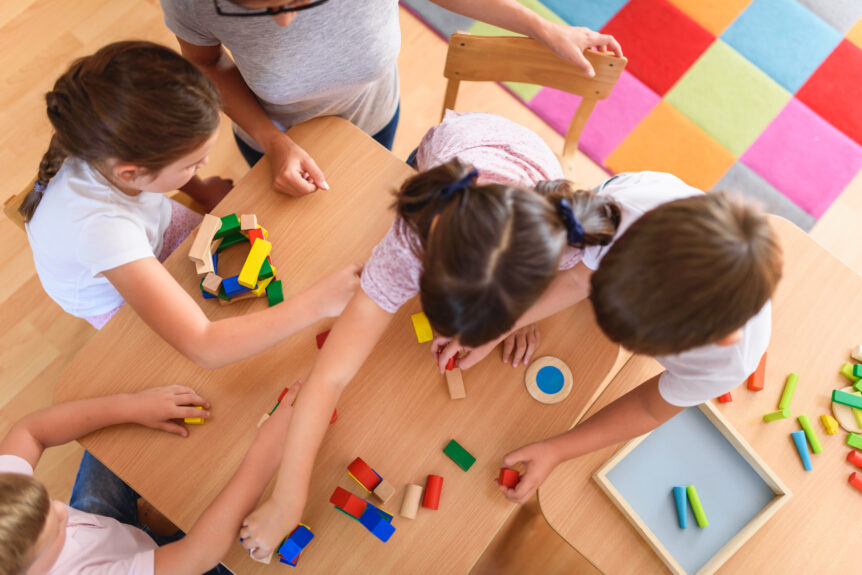 Preschool teacher with children playing with colorful wooden did