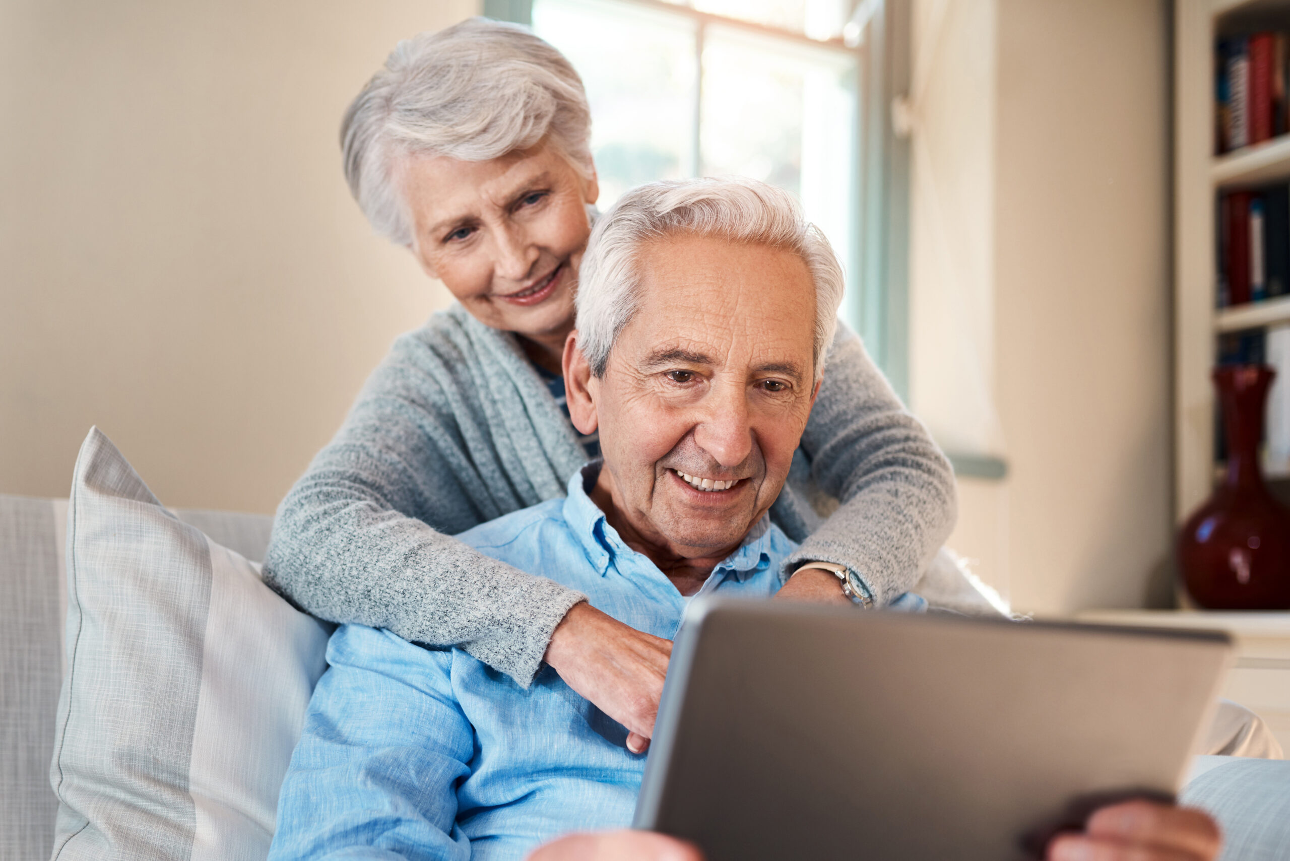 Older couple, happily reading something from their tablet together. 