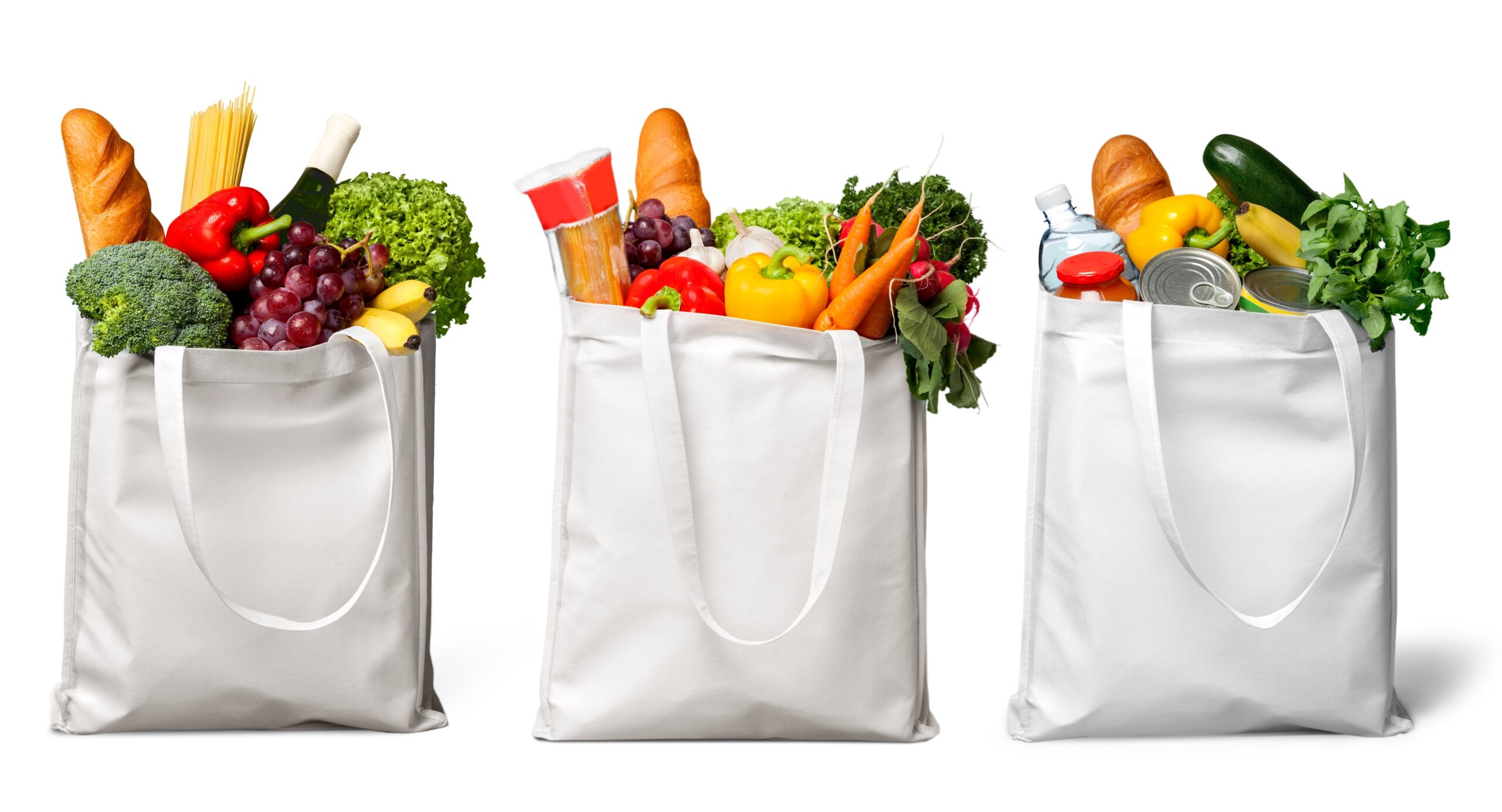 A photo of 3 bags of groceries filled with produce, bread, and pasta. 